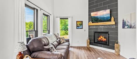 Cozy living room with gas fireplace, comfortable furniture, Smart TV, and lots of natural light.