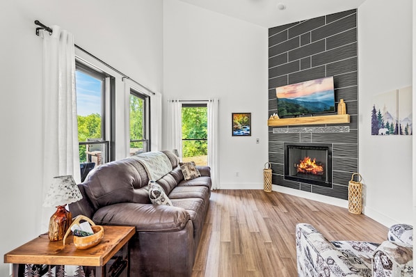 Cozy living room with gas fireplace, comfortable furniture, Smart TV, and lots of natural light.