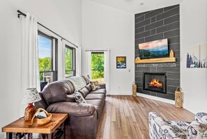 Cozy living room with gas fireplace, comfortable furniture, Smart TV, and lots of natural light.