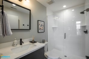 Step into a clean and sleek bathroom retreat. A refreshing shower and a mirror are complemented by all the essential amenities. Experience a serene oasis where style meets functionality, providing a pristine space for your daily self-care routine.