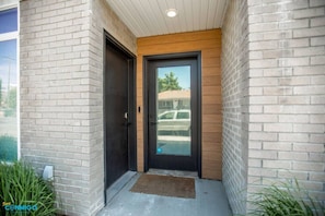 Welcome to the elegant condo entrance. The door reflects sophistication, adorned with a mirror that adds a touch of style. Step into a world of comfort and luxury as you enter this inviting living space, where every detail is designed to impress.