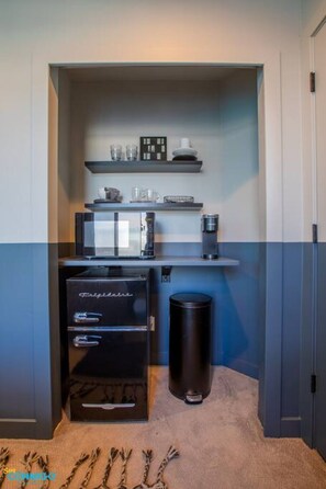 Stylish black mini fridge topped with a microwave, accompanied by glasses and plates. This sleek setup combines functionality and modern design, making mealtime a breeze in your well-equipped kitchen.