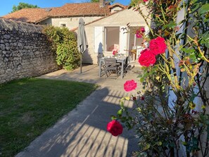 La cour ensoleillée pour prendre ses repas. Au fond, la chambre du rez-de-chaussée (grand lit double)