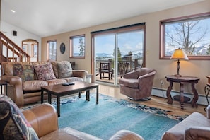 The living room is filled with natural light from the multiple windows in the space all providing beautiful views over the surrounding trees and mountains.