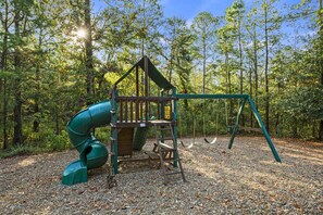 The backyard is a paradise with a cozy fire pit and a playground for endless fun.