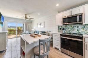 interior - Kitchen and island with seat overlooking living area and deck access