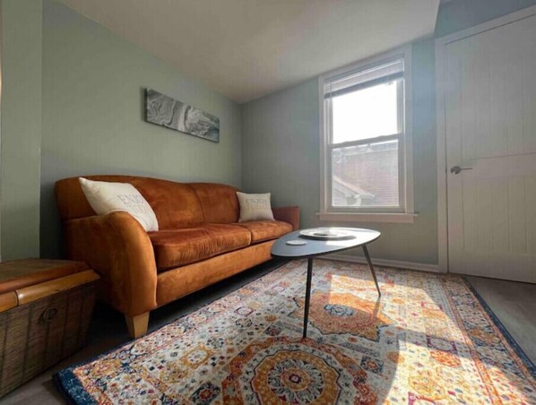 The living room boasts a bright, comfortable microfiber couch and coffee table.