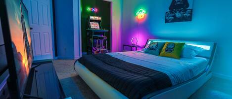 Star Wars themed room with queen bed, neon light features and arcade and tv