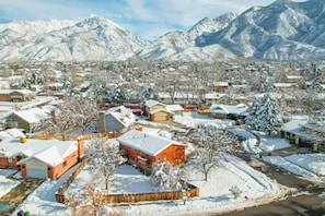 Elevate your senses with a breathtaking aerial view. Gaze upon a winter wonderland as the neighborhood sparkles beneath a blanket of snow, with majestic mountains as the backdrop. Immerse yourself in the magical beauty of this snowy paradise.