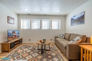 Indulge in luxurious relaxation with a plush sofa, a sleek coffee table, and a captivating TV setup. The carefully curated paintings on the walls add an artistic touch to the space, while the ample natural light streaming through the four large.