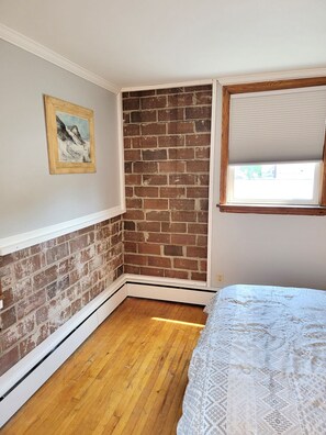 2nd photo of queen bed behind divider showing the original brick.