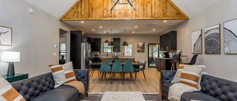 Luxury cabin decor with leather sofas, open floorplan, with gorgeous wood beams and vaulted ceiling