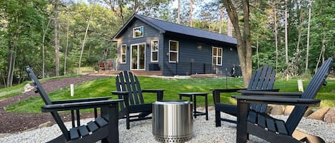 Fire pit and home with a backdrop of tall pines