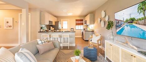 A modern living room exuding a resort-like ambiance, featuring a comfortable couch, a sleek center table, and a large TV for entertainment.