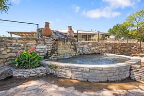 Unwind beside this charming stone fountain with cascading water and vibrant garden views.
