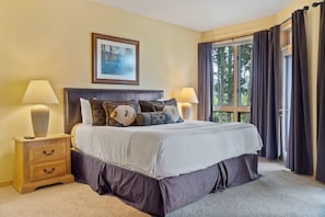 The master suite boasts impressive views out of the soaring windows, a king-size bed, a mounted TV and an attached full bathroom.