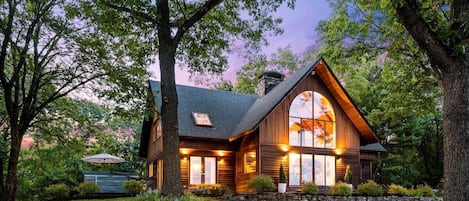 The house aglow at dusk, surrounded by 8 scenic acres
