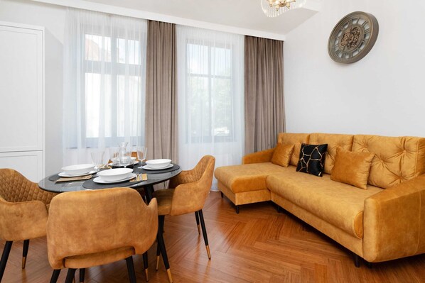 A cozy living and dining area featuring a vibrant mustard sofa, a round dining table, and warm lighting.
