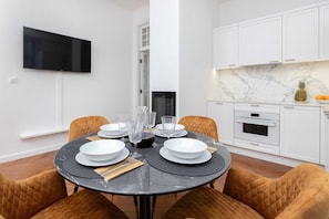 A dining area with a round table, mustard chairs, and a mounted TV, blending functionality and style.
