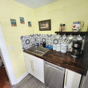 Coffee bar next to refrigerator.