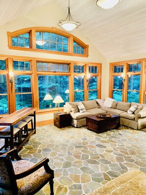 Tavern room with sleeper sofa, radiant flooring, 80” TV & bar table.