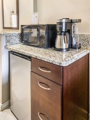 A convenient efficiency kitchen with a coffee maker, fridge, and microwave.