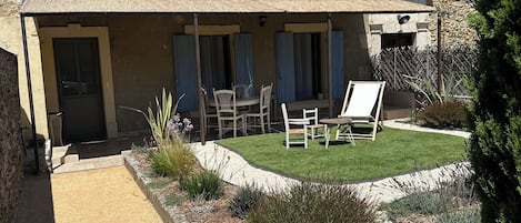 La terrasse ombragée donnant sur son typique jardin fleuri.