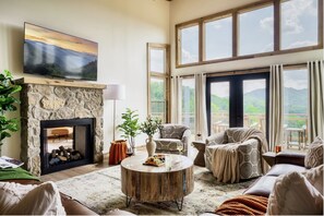 Our inviting upper level living room boasts a stunning outdoor view, a cozy fireplace, and plush couches, creating a perfect retreat for making memories and cherishing moments.