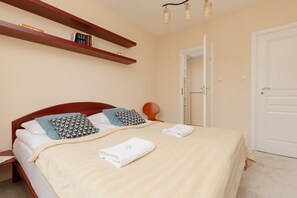 A cozy bedroom featuring a double bed with soft linens and decorative shelves on the wall.
