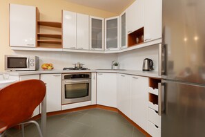 A modern kitchen with white cabinetry, wooden accents, and all essential appliances for convenient cooking.
