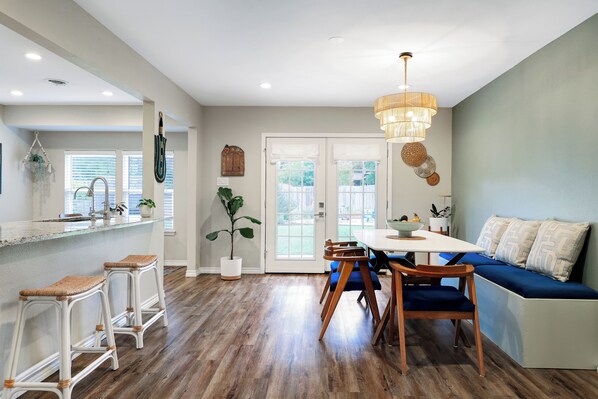 Open dining with table for 6, 2 bar stools & vibrant live plants throughout.