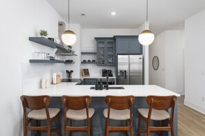 Fully-stocked kitchen with high-end appliances and seating for 4 at the kitchen counter.