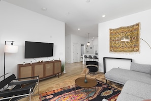 Colorful, cozy living room with a Smart TV, comfortable sectional, and a balcony.