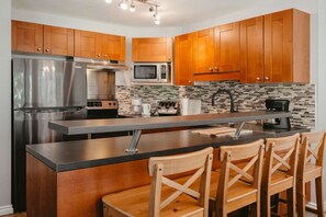 A full kitchen including four bar stools to sit at.