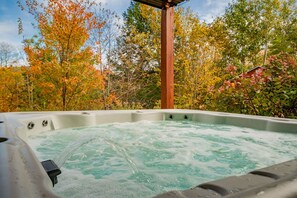 Soak in professionally maintained hot tub overlooking scenic wooded landscape