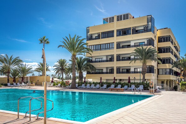 Pool area with sunbeds and palm trees