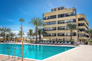 Pool area with sunbeds and palm trees