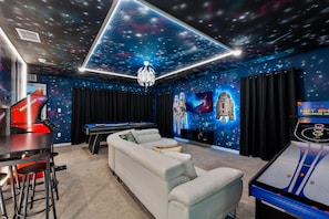 Embark on a galactic adventure with a 65-inch TV, arcade games, pool table, and Star Wars decor. May the fun be with you!