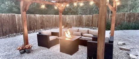 Pergola with fire pit in the spacious backyard that is fully fenced and private.