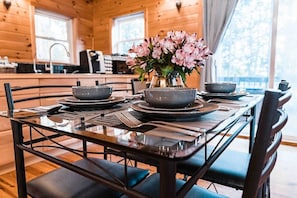 Ready for a cozy meal or a morning coffee, this beautifully set dining table in the Sunset Chalet offers the perfect setting. Enjoy a warm ambiance with modern touches and a view of nature right outside.