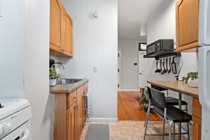 The kitchen features a wooden cabinet, stove, and various cooking utensils.