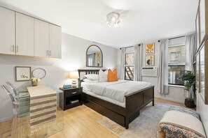 Bright and inviting bedroom with a queen-size bed, modern decor, and natural light from large windows. A stylish space to unwind.