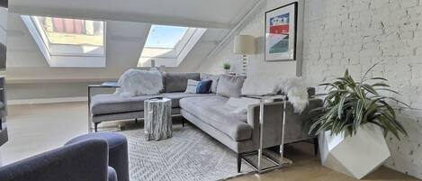 Bright open concept living space with skylights, ultra comfortable West Elm sofa and gas fireplace.