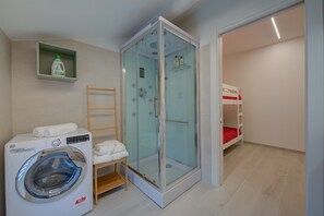 Bathroom with hydro-massage shower, washbasin, bidet, toilet and washing machine