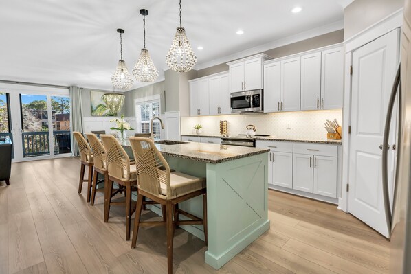 Gorgeous kitchen remodeled with new appliances, upgraded backsplash, under cabinet lighting, and new pedants over large island.