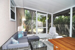 A screened-in porch with lots of seating and a dining table