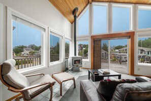 Open living and dining area with wood stove, access to oceanview deck.