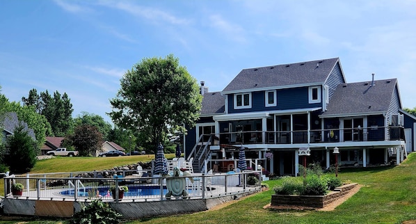 Back of house with pool and hot tub on the deck