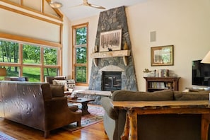 The inviting living room boasts plush furnishings all centered around the stone hearth fireplace.