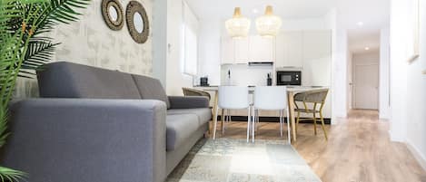 Sala de estar con sofá-cama, comedor, cocina abierta y Smart TV.